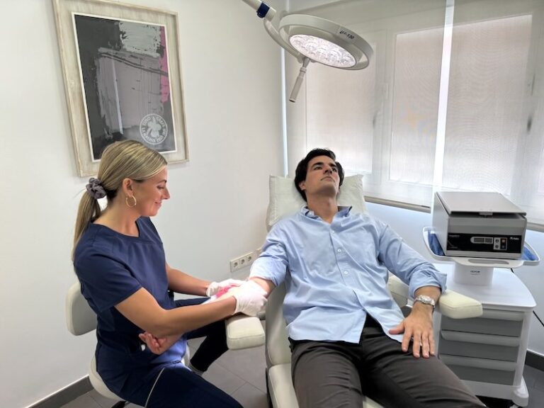 Enfermera especialista de Folika Hair Clinic realizando una extracción de sangre a un paciente relajado en consulta, paso previo para preparar el Plasma Rico en Plaquetas (PRP) capilar.