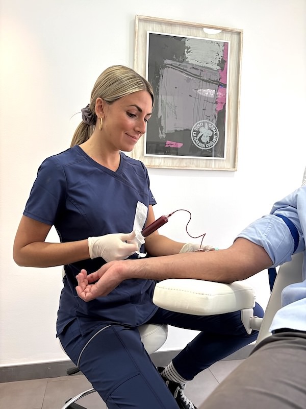 Enfermera especialista de Folika Hair Clinic realizando cuidadosamente una extracción de sangre del brazo de un paciente para preparar su tratamiento de Plasma Rico en Plaquetas (PRP).