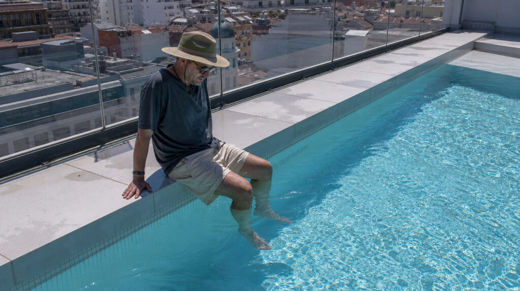Un hombre nadando en una piscina con gorro de natación negro y gafas, mostrando cómo proteger el cuero cabelludo del cloro tras un injerto capilar en Folika Hair Clinic.